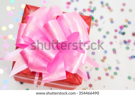red gift box with pink ribbon and bow on white paper background.