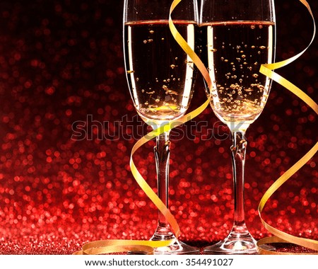 glasses of champagne with yellow holidays ribbons, on red background