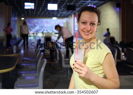 Portrait of a happy woman with milkshake in the hands of the bowling hall