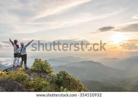 Young happy tourist on top of a mountain enjoying valley view Royalty-Free Stock Photo #354510932