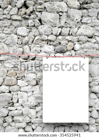 Close-up of one hanged paper sheet frame with pegs on ancient stone wall background