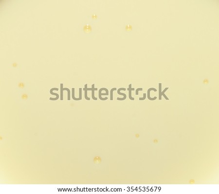 Pale yellow texture of condensed milk with bubbles. Pale yellow water with bubbles. Closeup