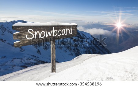 Wooden sign Snowboard. Ski-track with Caucasus mountains on background. Ski vacation panorama on top of the mountain. No people.