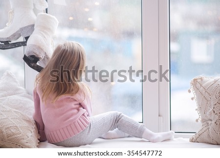 The little girl in a white sweater pink by the window awaiting the appearance of Santa Claus, New Year's Eve