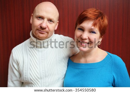 Portrait of a bald man in white sweater and a happy red-haired woman 