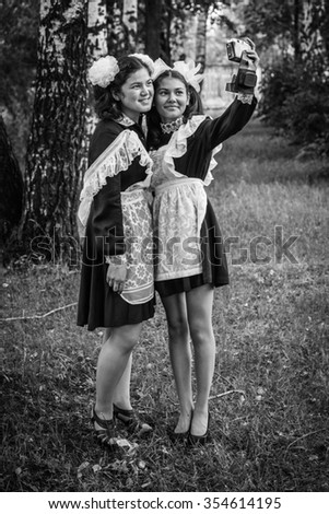 Two schoolgirls in school uniform graduates make a picture for memory. Black and white photography.