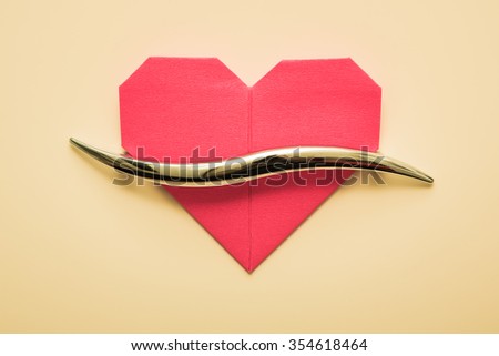 Red paper Valentine's Day heart against the door handle.