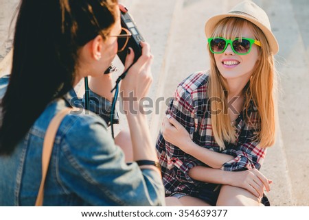 two young beautiful happy stylish hipster girls, friends together, smiling, happy, cool accessories, sunglasses, denim vintage style, having fun, summer trend outfit, taking pictures on vacation