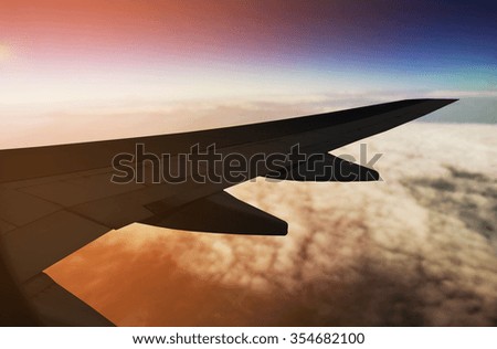 Airplane flying above clouds at sunset view from window- travel concept