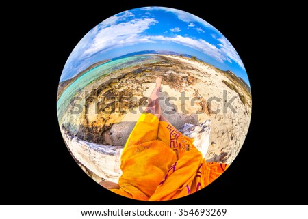 Picture taken with fisheye lens 8 mm, it represents the concept of sitting in heaven. A woman with orange sarong sitting on branch in Simos Beach, Elafonisos Island, Peloponnese, Greece.