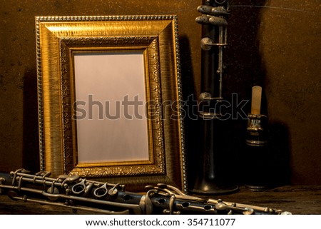 Still life of picture frame on wooden table with clarinet.
