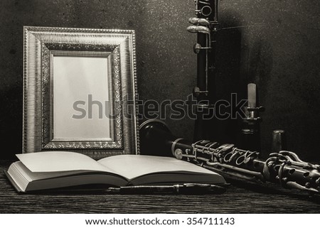 Still life of picture frame on wooden table with clarinet.