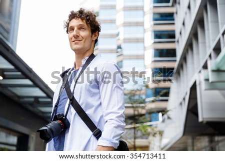 Happy male tourist in city walking with camera