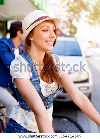 Beautiful young woman riding on bike in city