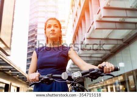 Young woman in business wear commuting on bicycle in city
