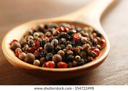 Wooden spoon with pepper on the table, close-up
