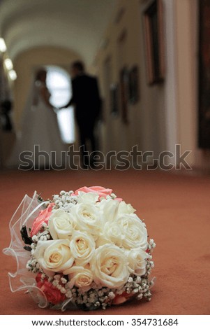 lush wedding bouquet red and beige colors is on the floor in the Museum in the background going into the distance the newlyweds