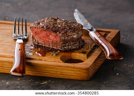 Filet Mignon Steak on wooden board on black background Royalty-Free Stock Photo #354800285