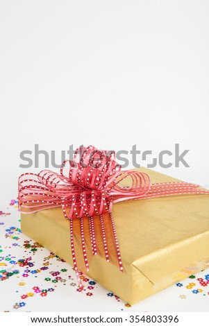 Beautiful gold present box with red bow on white paper backgound
