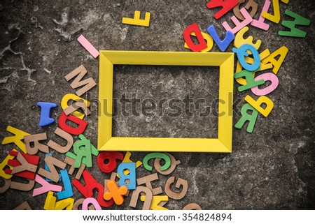 Yellow color frame with wooden alphabet on the floor. The rusty floor makes a nice composition for education concept. This photo can use as education concept.  