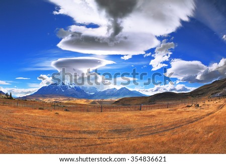 The Chile National Park "Torres del Paine". Incredible shaped clouds formed by glaciers glisten in the sun. On the horizon are seen mountains with snow-capped peaks. Picture taken with a fisheye lens