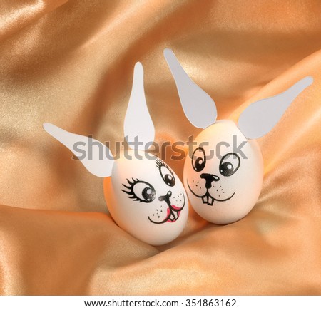 easter theme with bunny-painted eggs in golden satin background