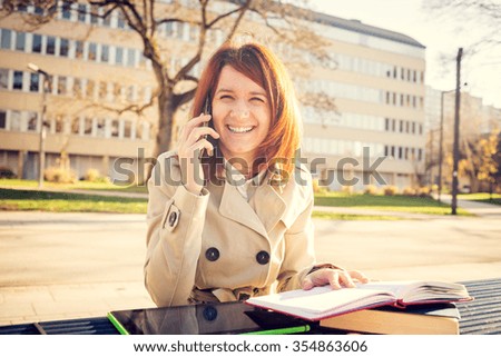 Smiling young woman student talking on mobile phone using tablet in campus university.Young smiling student outdoors with tablet.Life style.City