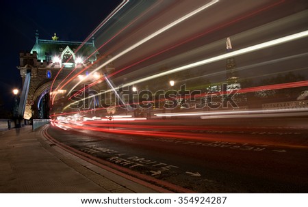 London tower Bridge, UK, at night with cars and buses leaving colorful light traces. 