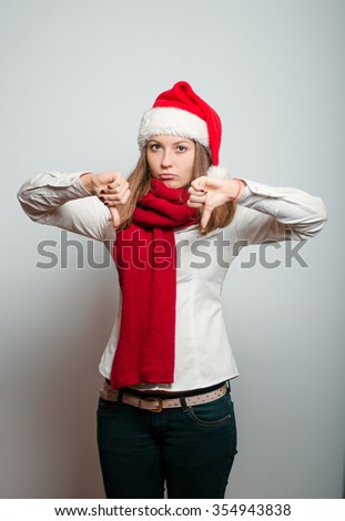 Santa girl showing thumbs down. Christmas hat isolated portrait of a woman on a gray background, studio photo.