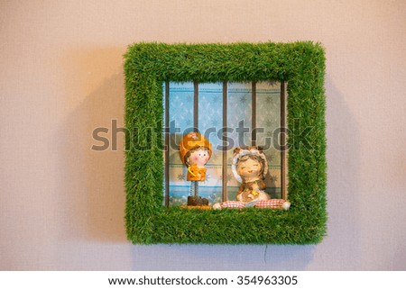 The dolls in grass photo frame under warm white light.