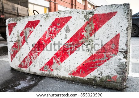 closeup photo of concrete road block with warning red and white diagonal striped pattern