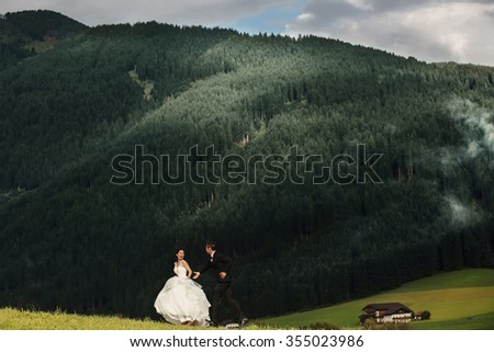 Beautiful stylish Asians bride and groom walking and having fun in alpine meadows in Italy, Trentino Alto Adige