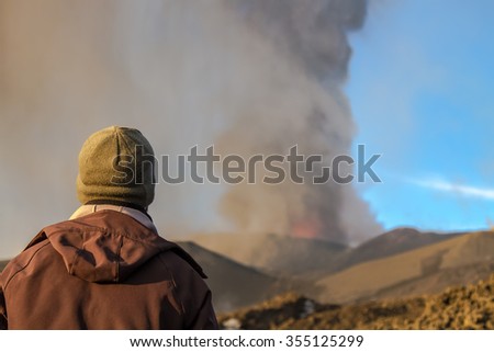 Boy looks the eruption of Volcano . Mount Etna erupting from the crater Voragine
