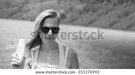 Sunscreen woman applying suntan lotion showing bottle. Beautiful smiling happy caucasian woman with suntan cream in plastic container during summer travel vacation