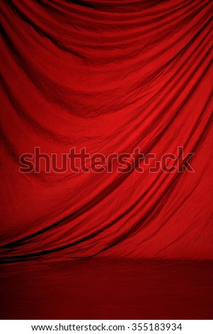 Traditional red canvas or muslin fabric cloth studio backdrop or background, suitable for use with portraits, products and concepts such as stage, theater or performance. Royalty-Free Stock Photo #355183934