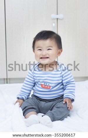 Cute Chinese baby boy sitting on a white blanket, shot in Beijing, China