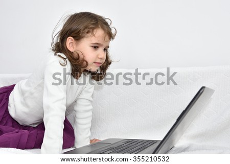Cute young girl watching the cartoon on a laptop at home