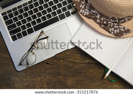 Vintage tone image of notebook, glasses, hat and laptop on wooden table