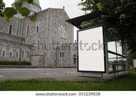 Blank billboard in a bus stop, with a church in the background