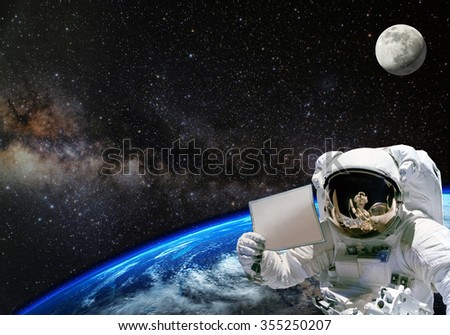 Astronaut holding blank paper with earth on the background. Elements of this image furnished by NASA.