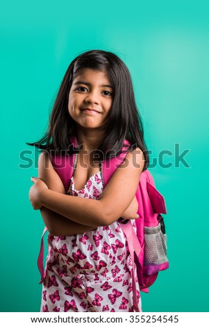 Off to school concept - Cute little indian girl standing with school bag, isolated over green background