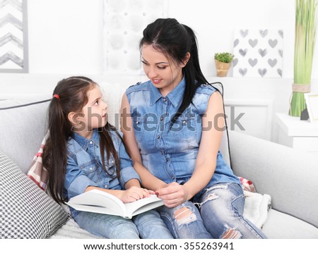 Mother and daughter reading book on the sofa