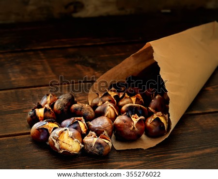 roasted chestnuts in paper bags on a wooden background Royalty-Free Stock Photo #355276022