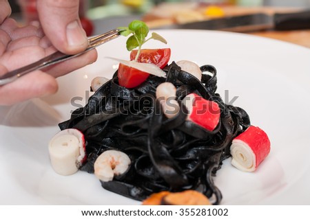 Chef Completing black tagliatelle with sea food