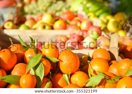 Bright picture of oranges with fresh fruits and vegetables at market in boxes on the background