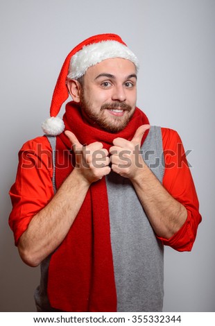 Man showing everything is OK. Happy Businessman wearing a Santa hat on New Year's corporate parties. Studio photo, isolated on a gray backgroundrties. Studio photo, isolated on a gray background