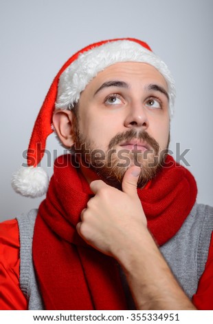 The man remembers something. Happy Businessman wearing a Santa hat on New Year's corporate parties. Studio photo, isolated on a gray background