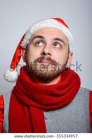 The man remembers something. Happy Businessman wearing a Santa hat on New Year's corporate parties. Studio photo, isolated on a gray background