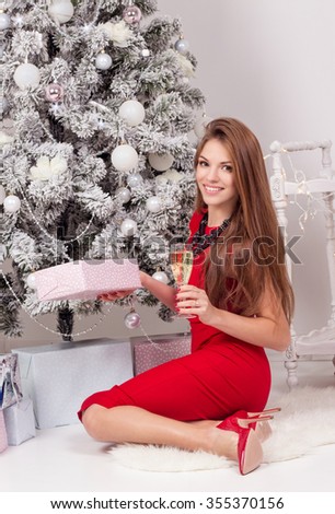 Young beautiful woman in a red dress near a Christmas tree. New Year. Christmas.