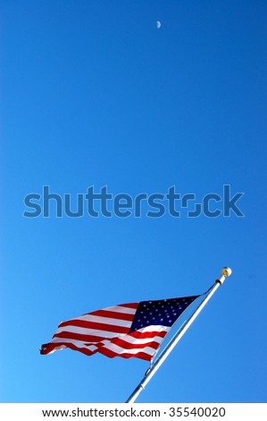 American flag waving on flagpole against blue sky.
